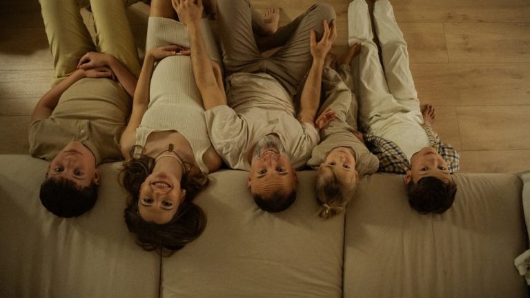 Five family members relaxing together at home, enjoying a warm moment on the floor with smiles.